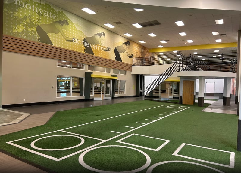 Interior of a modern U.S. fitness center with turf training area, motivational wall graphics, and mezzanine design, reflecting evolving trends in gym facility development and wellness investments across the 2025-2030 U.S. fitness industry outlook.