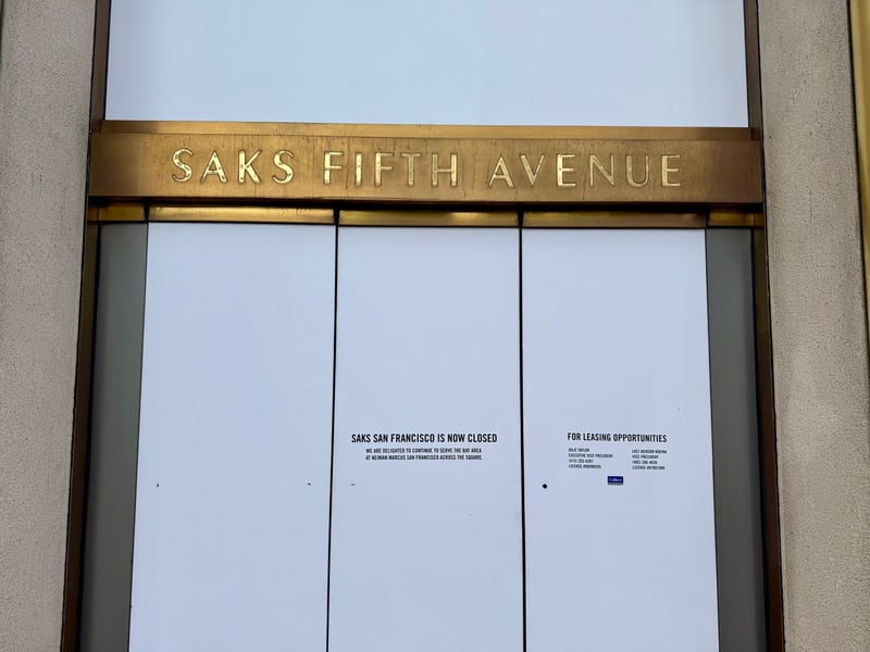 The shuttered Saks Fifth Avenue entrance in San Francisco, its gold lettering above whited-out doors carrying a notice that the store is now closed and a sign offering the space for lease.