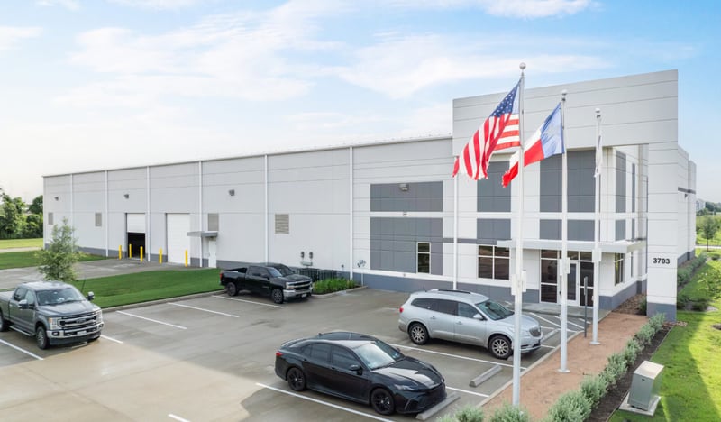 Newly built Class A industrial warehouse with dock-high doors, office frontage, and U.S. and Texas flags, address 3703