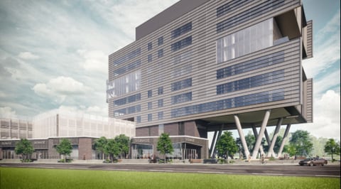 Architectural rendering of the Morrison Yard office tower, with upper floors of banded glass and metal cladding carried on large angled columns above an open ground level of retail storefronts, and a parking deck alongside.