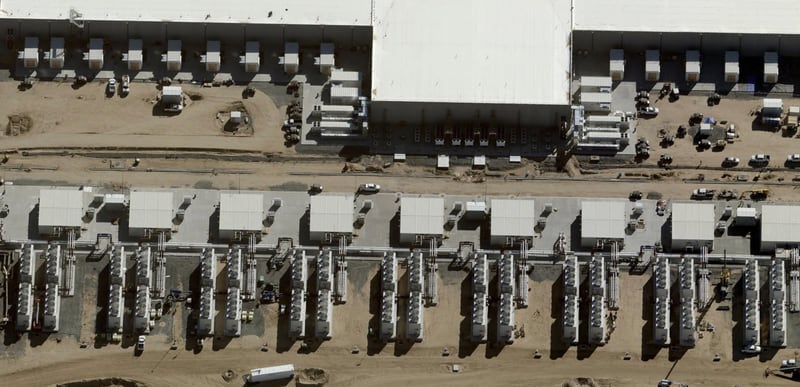 Aerial view of a data center under construction, two long buildings with rows of rooftop mechanical units.