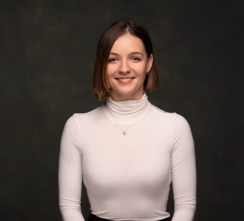 Viola Sauer, the MMCG analyst credited as this outlook's author, in a headshot: short brown hair, a white turtleneck and a smile against a dark studio background.